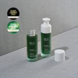 Two skincare bottles with 'RUA' branding on a gray surface, featuring awards badges.