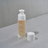 RUA Hydrate Elixir bottle with reusable white pump on a gray surface