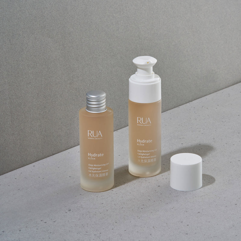 Two RUA Hydrate Elixir bottles on a gray surface with a neutral background