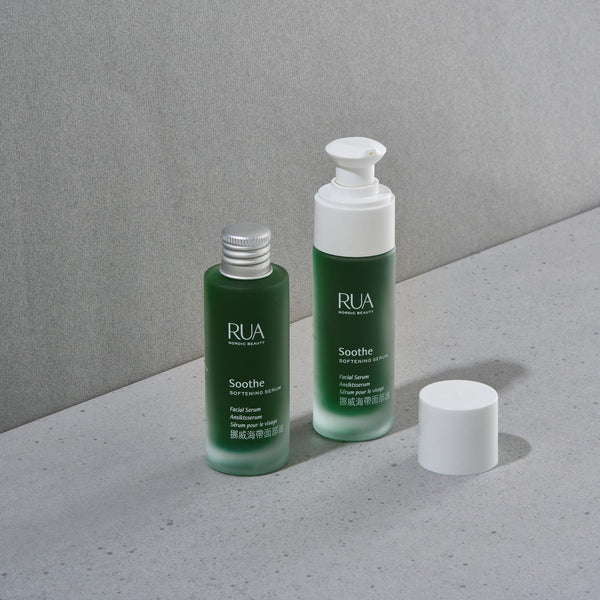 Two RUA Soothe Softening Serum bottles with white caps on a gray surface